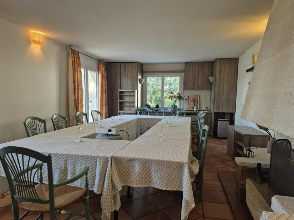 Salle de séminaire aménagée en U avec chaises vertes et carrelage en terre cuite