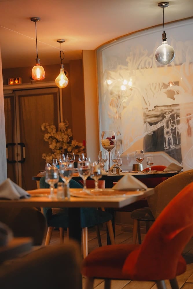 Salle du restaurant dressée pour un apéritif avec verres à pied et lumière chaleureuse
