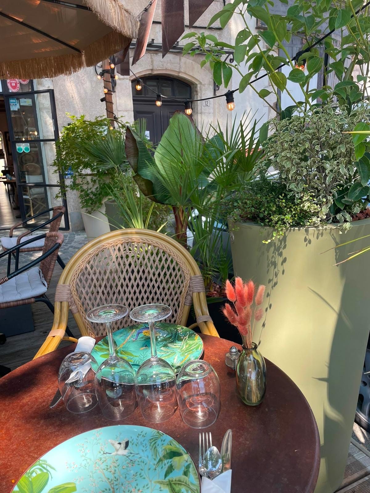 A table set on the terrace: tropical plates, rattan and lush greenery