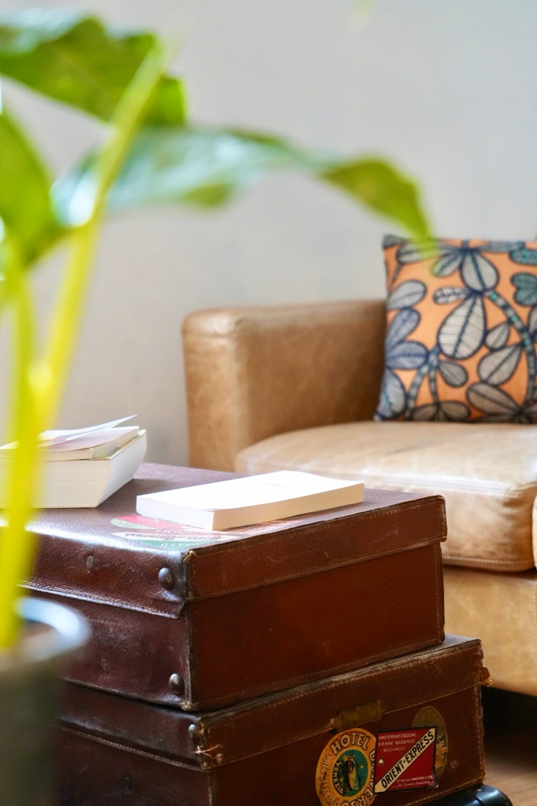 Antique travel trunks stacked beside the leather sofa