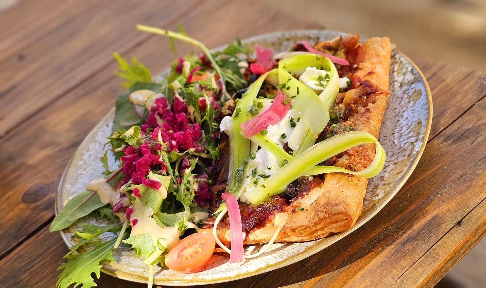 Thin tart with a colourful salad: asparagus shavings, pickles and flowers
