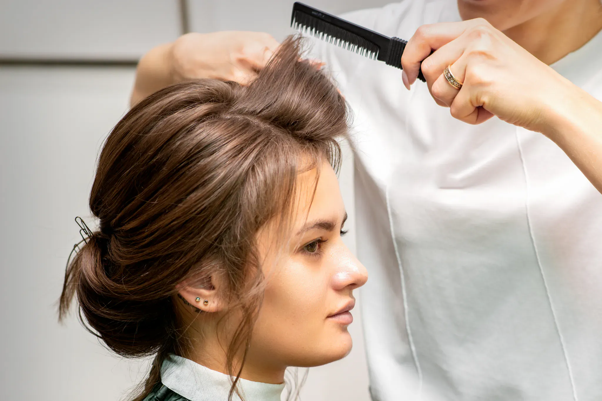 Coiffeuse peignant et coiffant les cheveux lissés d'une cliente en salon