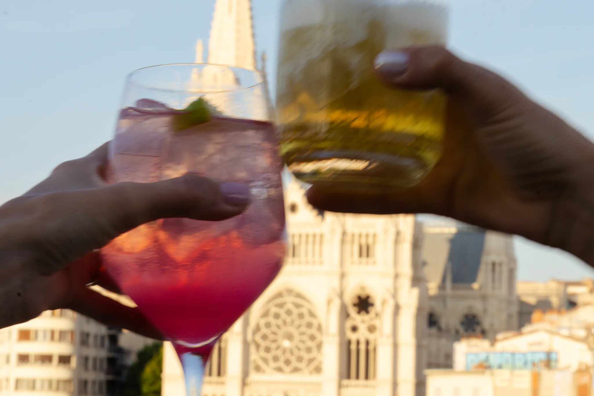 Deux verres trinqués en terrasse face aux flèches de l'église des Réformés au coucher du soleil