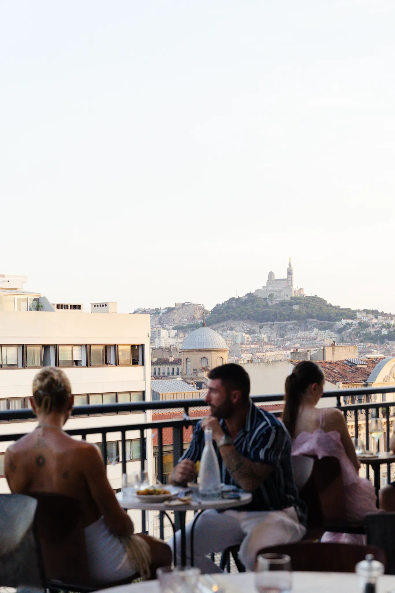 Convives déjeunant en terrasse avec vue sur Notre-Dame de la Garde