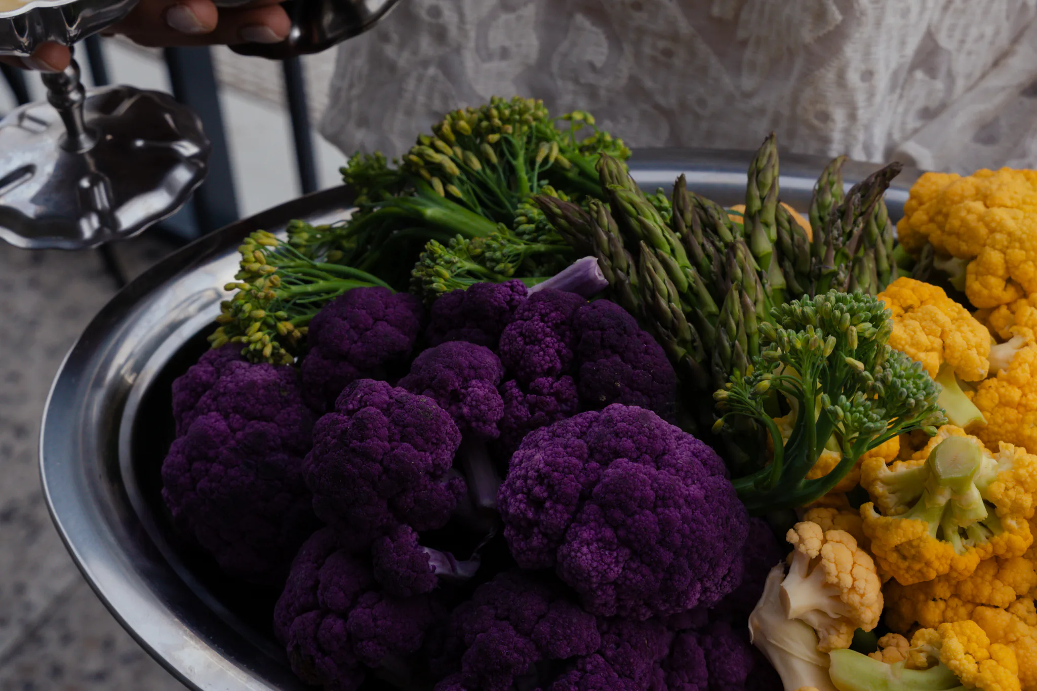 Plateau de légumes de saison — chou-fleur violet, chou-fleur jaune, brocolis et asperges — présenté en salle