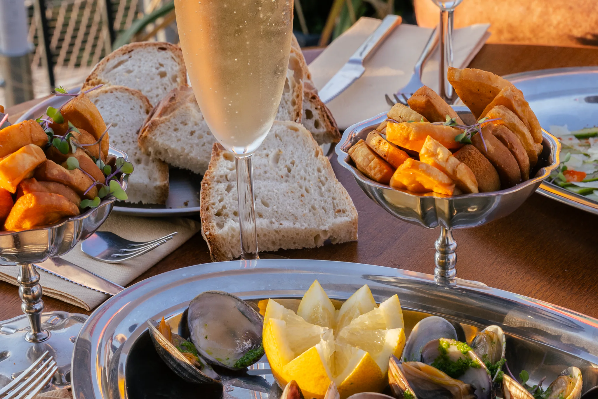 Table garnie de coquillages, croquettes et pain, avec deux coupes de champagne en terrasse