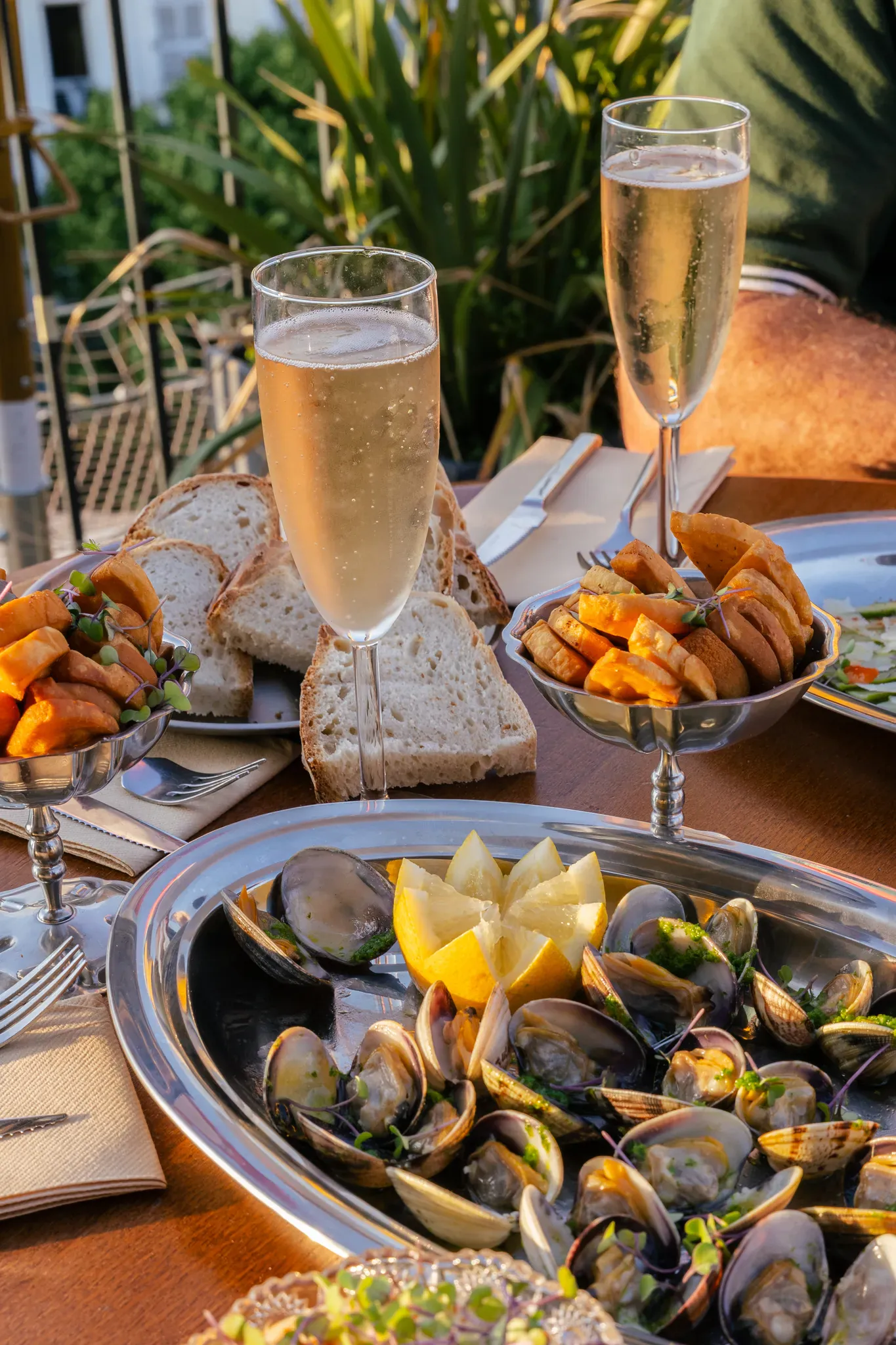 Table dressée en terrasse avec champagne, pain et plats à partager