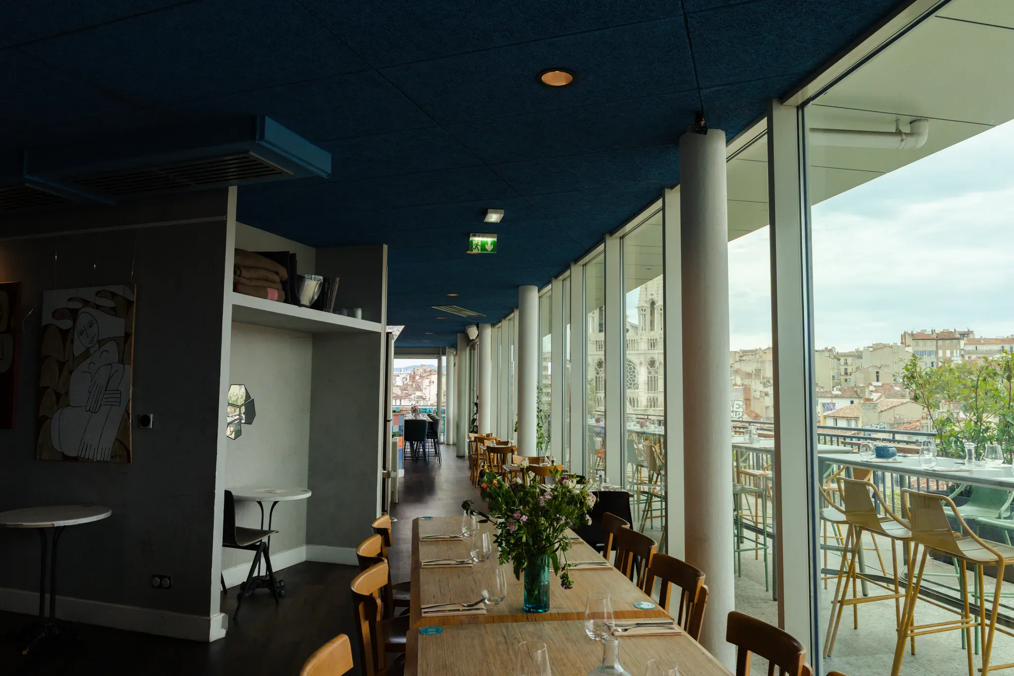 Allée de tables le long des baies vitrées, vue sur Marseille