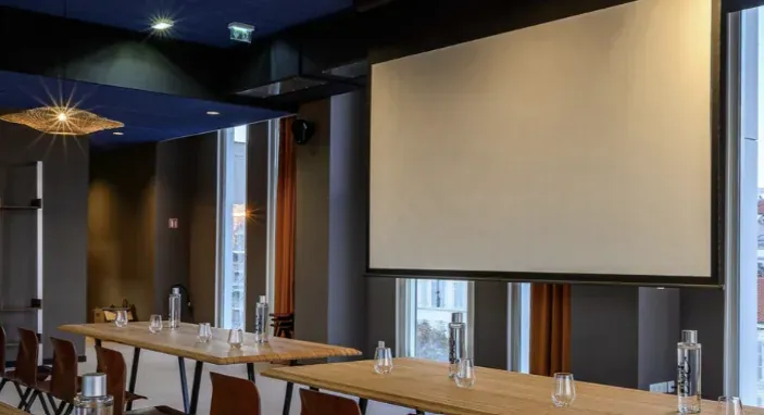 Salle du 3e étage en configuration réunion, écran de projection déroulé face aux tables