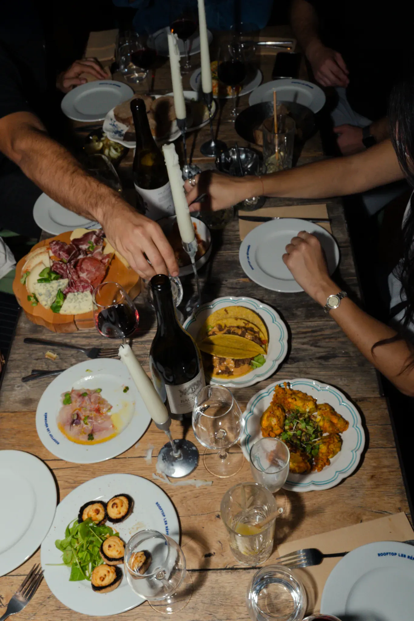 Table de partage vue du dessus : charcuterie, ceviche, vin et bougies