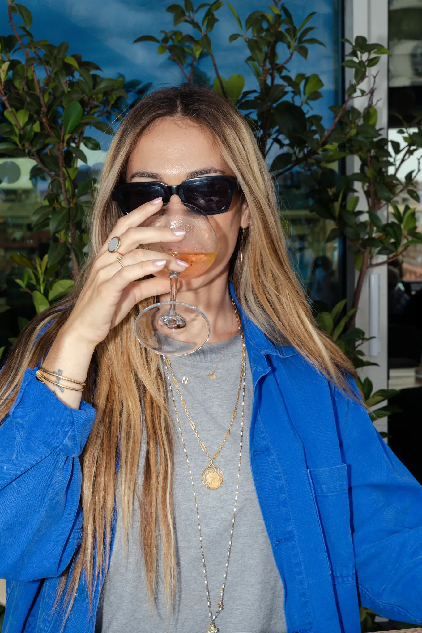 Convive en chemise bleue savourant un verre de rosé en terrasse