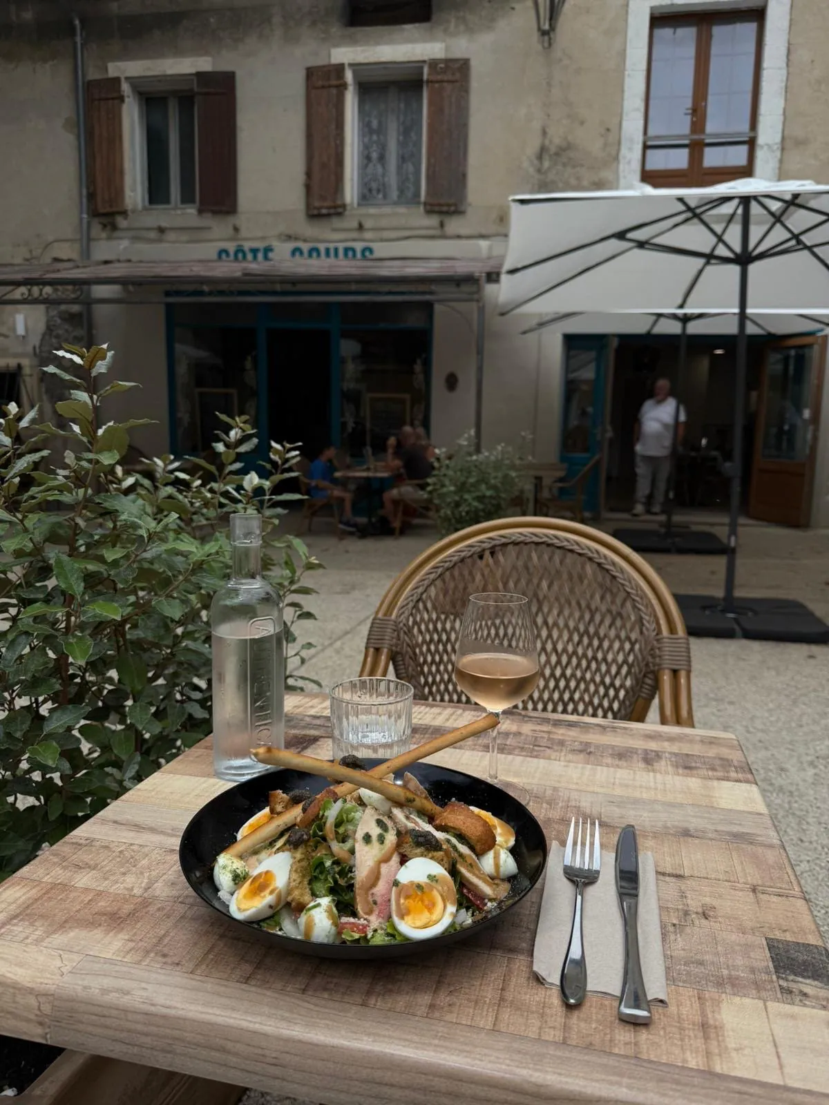 Salade de saison et verre de rosé servis en terrasse, l'enseigne Côté Cours en fond