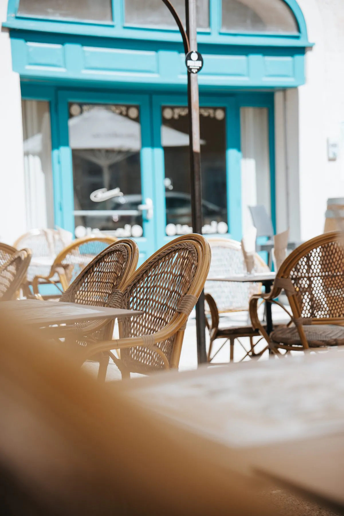 Les fauteuils en rotin de la terrasse devant la porte turquoise, avant le service
