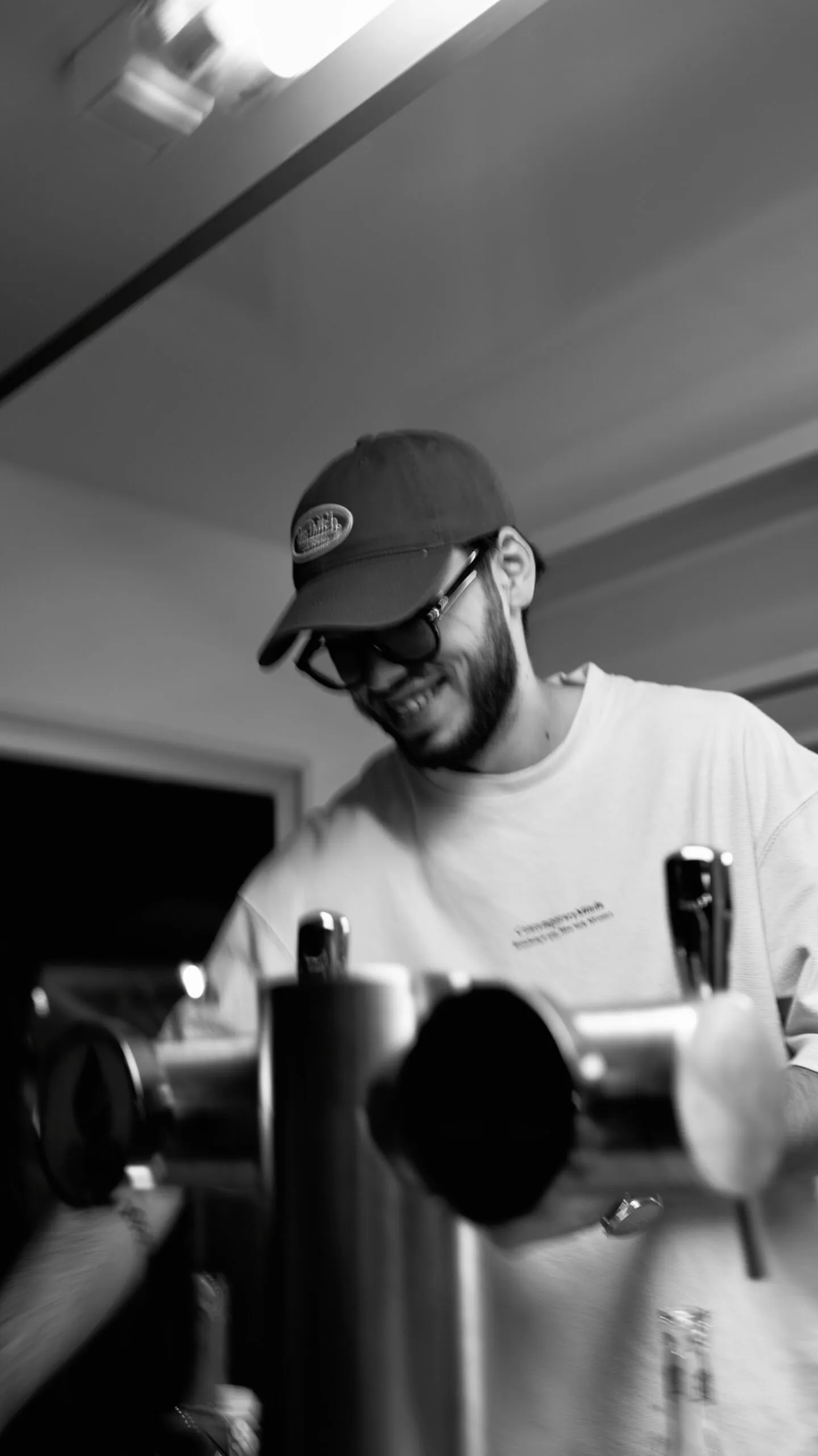 Le barman à la tireuse, sourire aux lèvres, à la nuit tombée