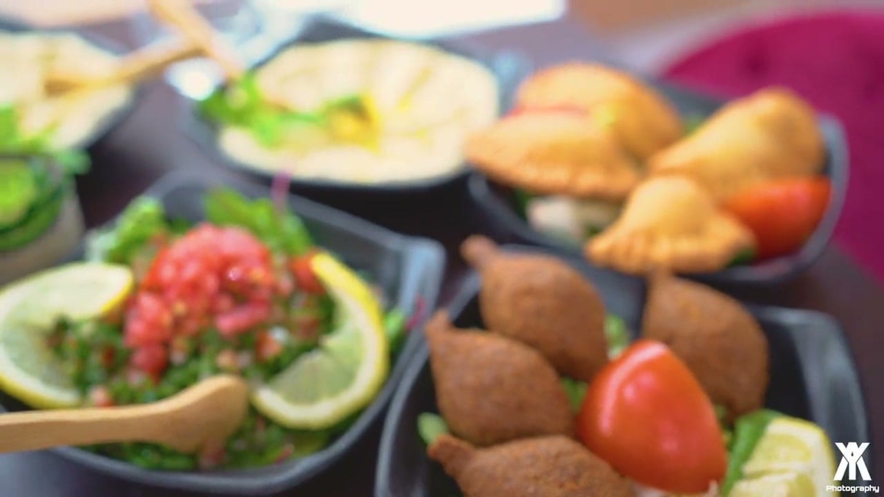 Assortiment de mezze libanais avec taboulé vert, kebbé frits et samoussas dorés sur une table