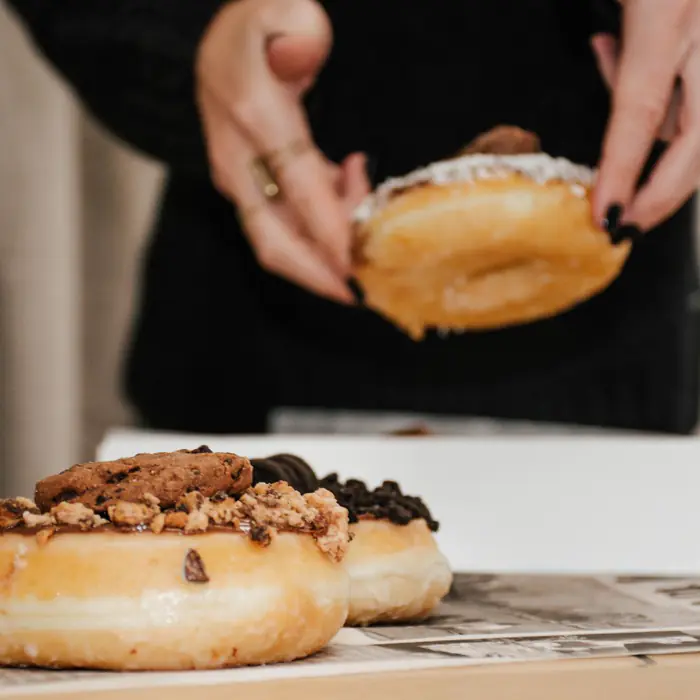 Deux mains tenant un donut au-dessus de la boîte
