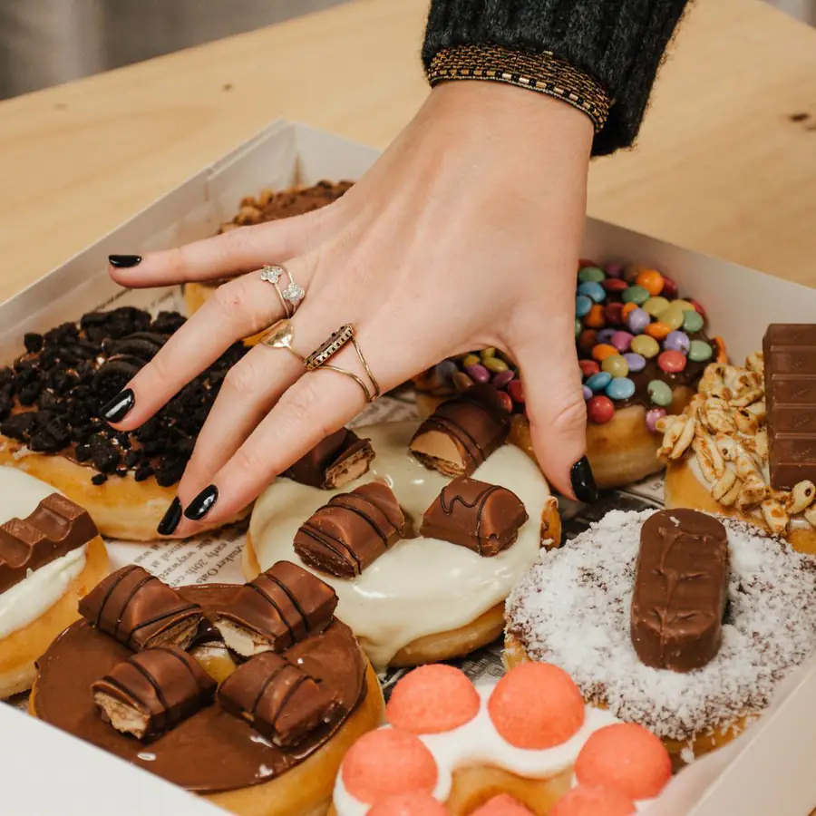 Une main prend un donut dans la boîte