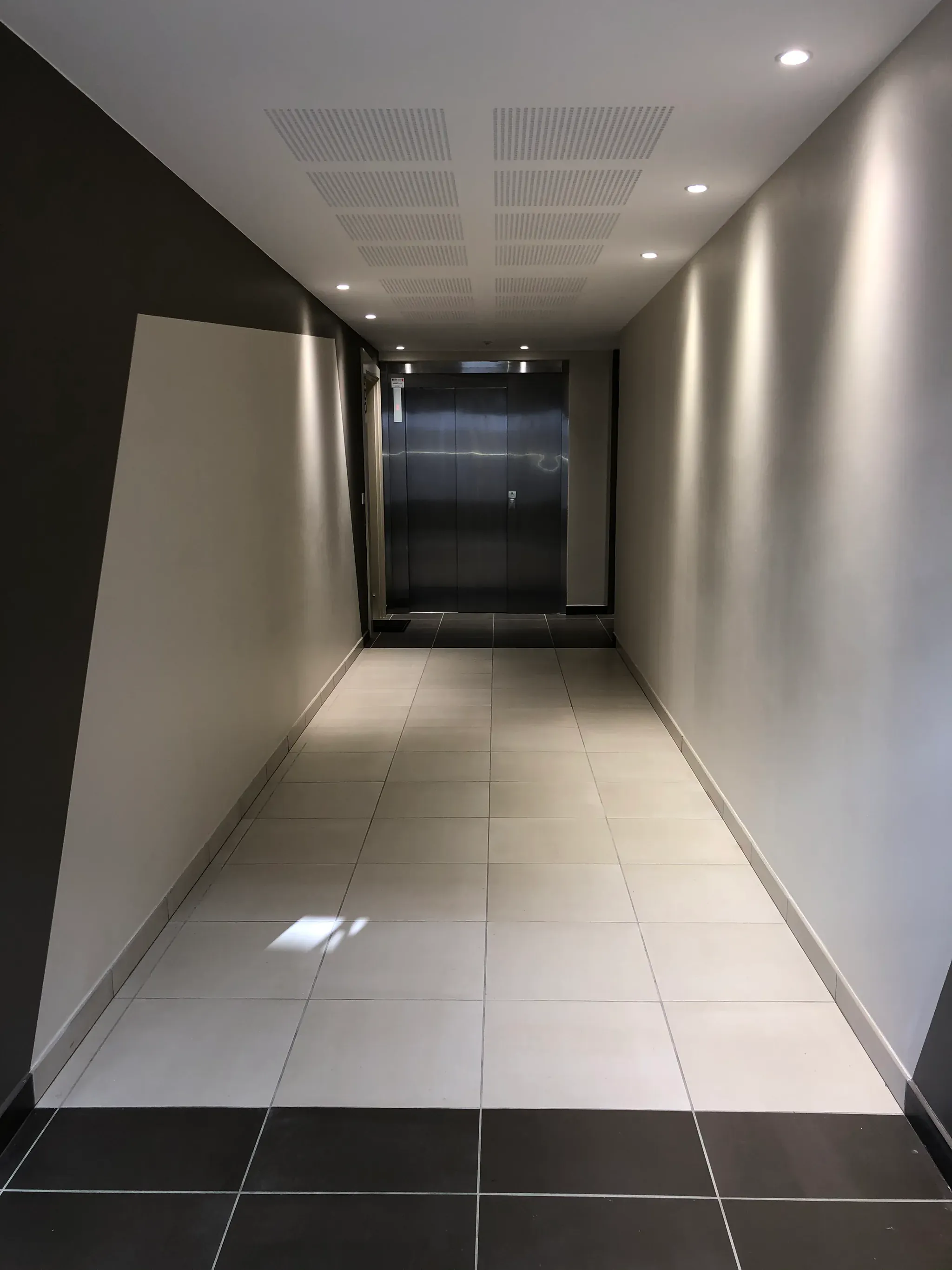 Couloir et zone de circulation d'un bâtiment menant à un ascenseur, cheminement d'évacuation exigeant