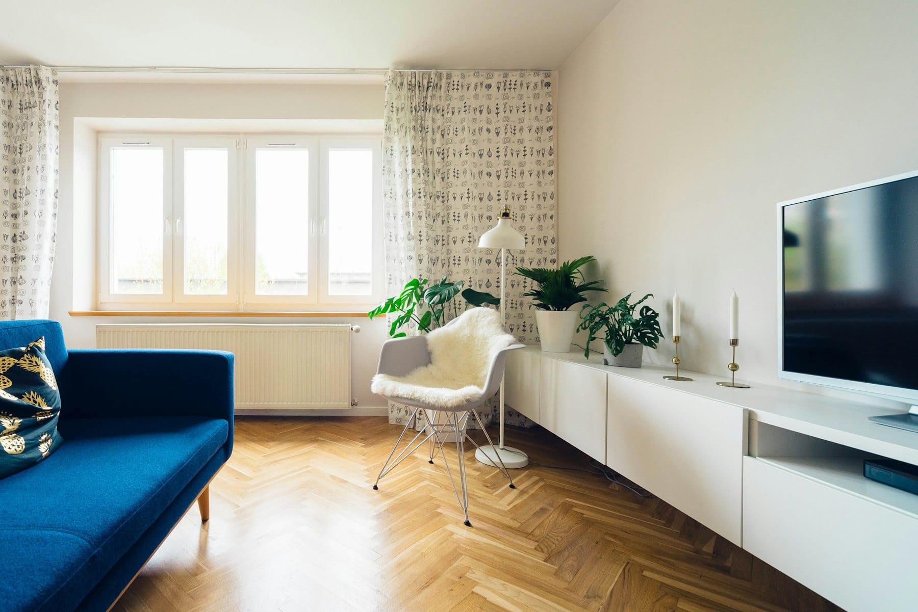 Salon au parquet en chevrons entretenu chaque semaine, canapé bleu et grande fenêtre