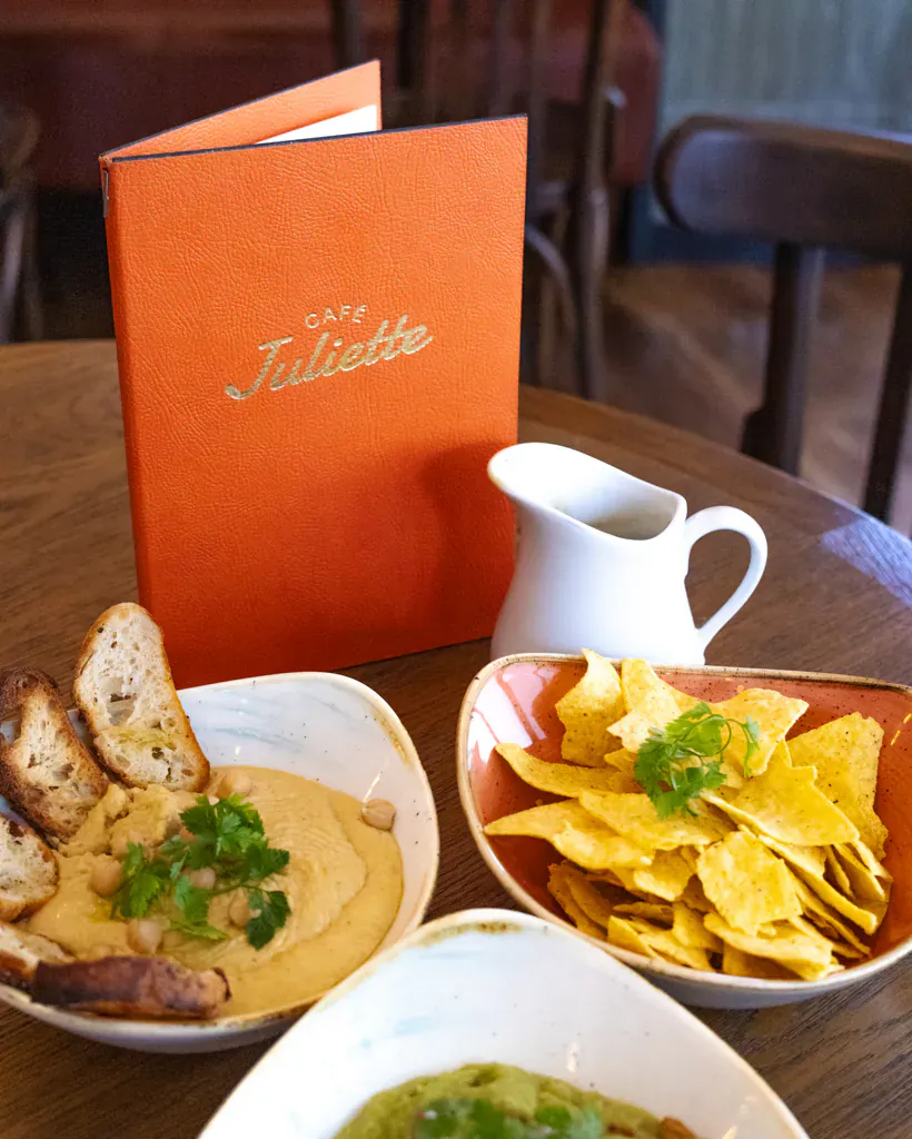 Menu d'un restaurant posé sur une table en bois entouré de bols à partager, pour cadrer un menu de groupe