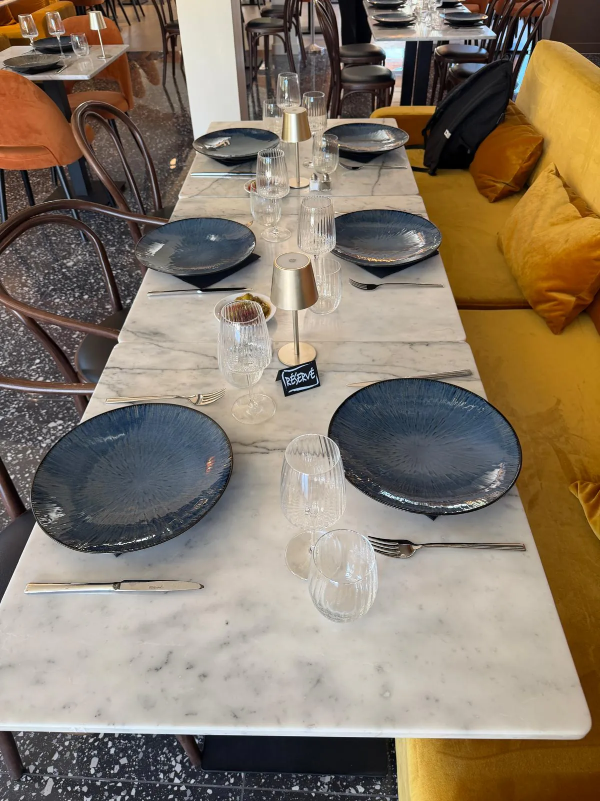 Table de restaurant en marbre dressée avec vaisselle et verres au restaurant Pakal, prête à accueillir.