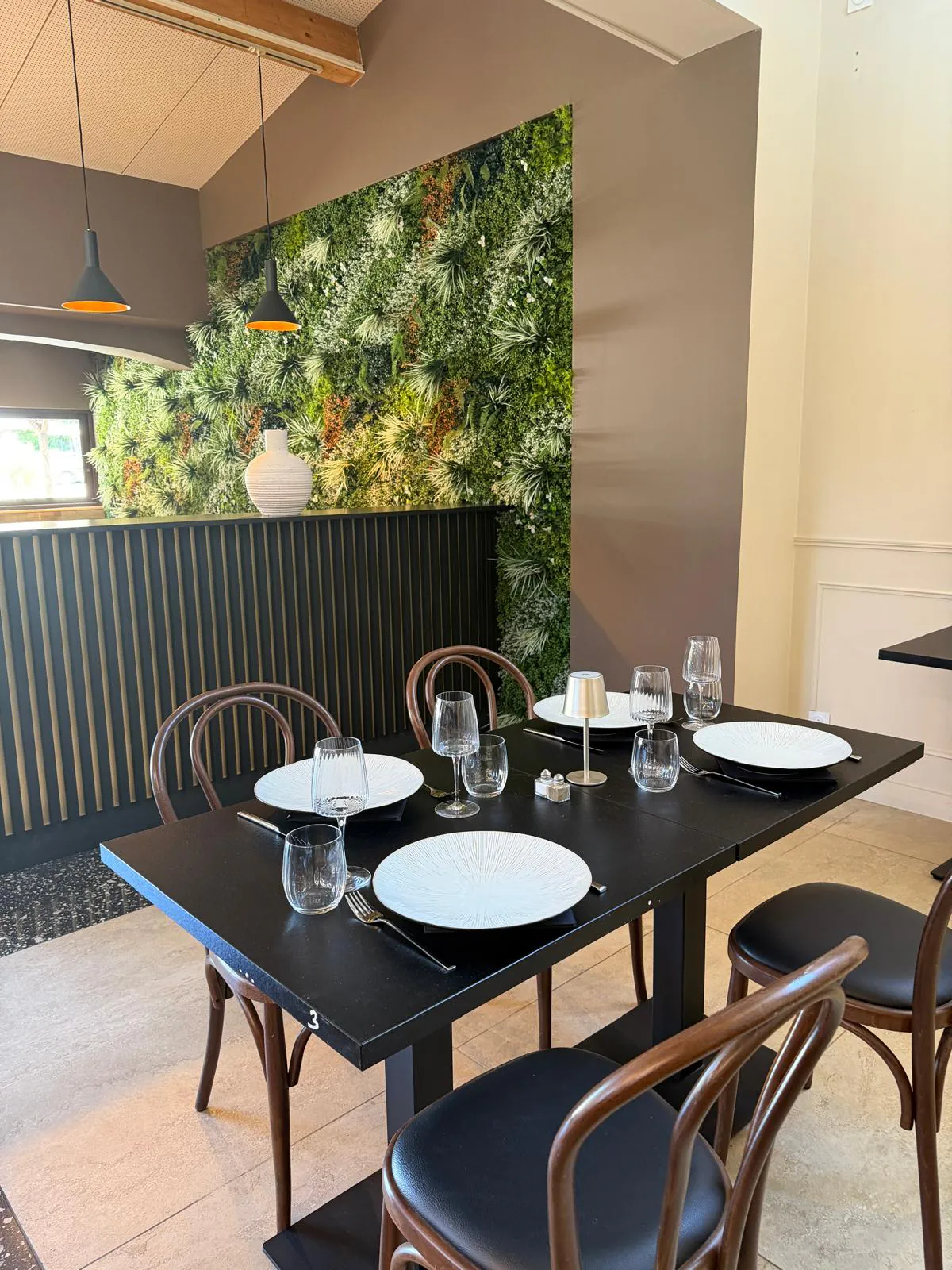 Table dressée pour quatre convives au restaurant Pakal, devant un mur végétal — l'esprit convivial de Bouc-Bel-Air.