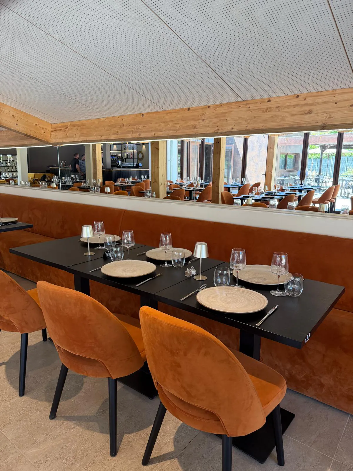 Salle lumineuse du restaurant Pakal aux banquettes de velours orange, dressée pour le déjeuner à Bouc-Bel-Air.
