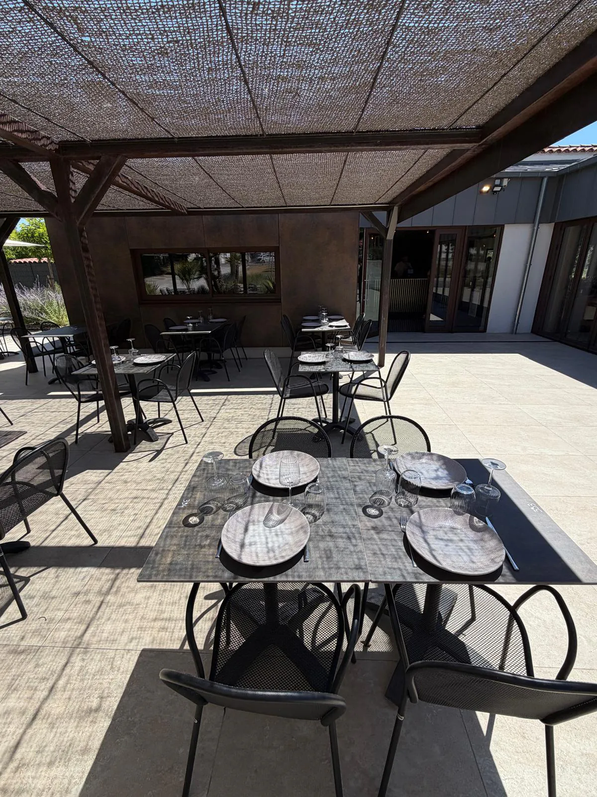 Outdoor terrace of Pakal restaurant in Bouc-Bel-Air with set tables and parasols under a pergola.