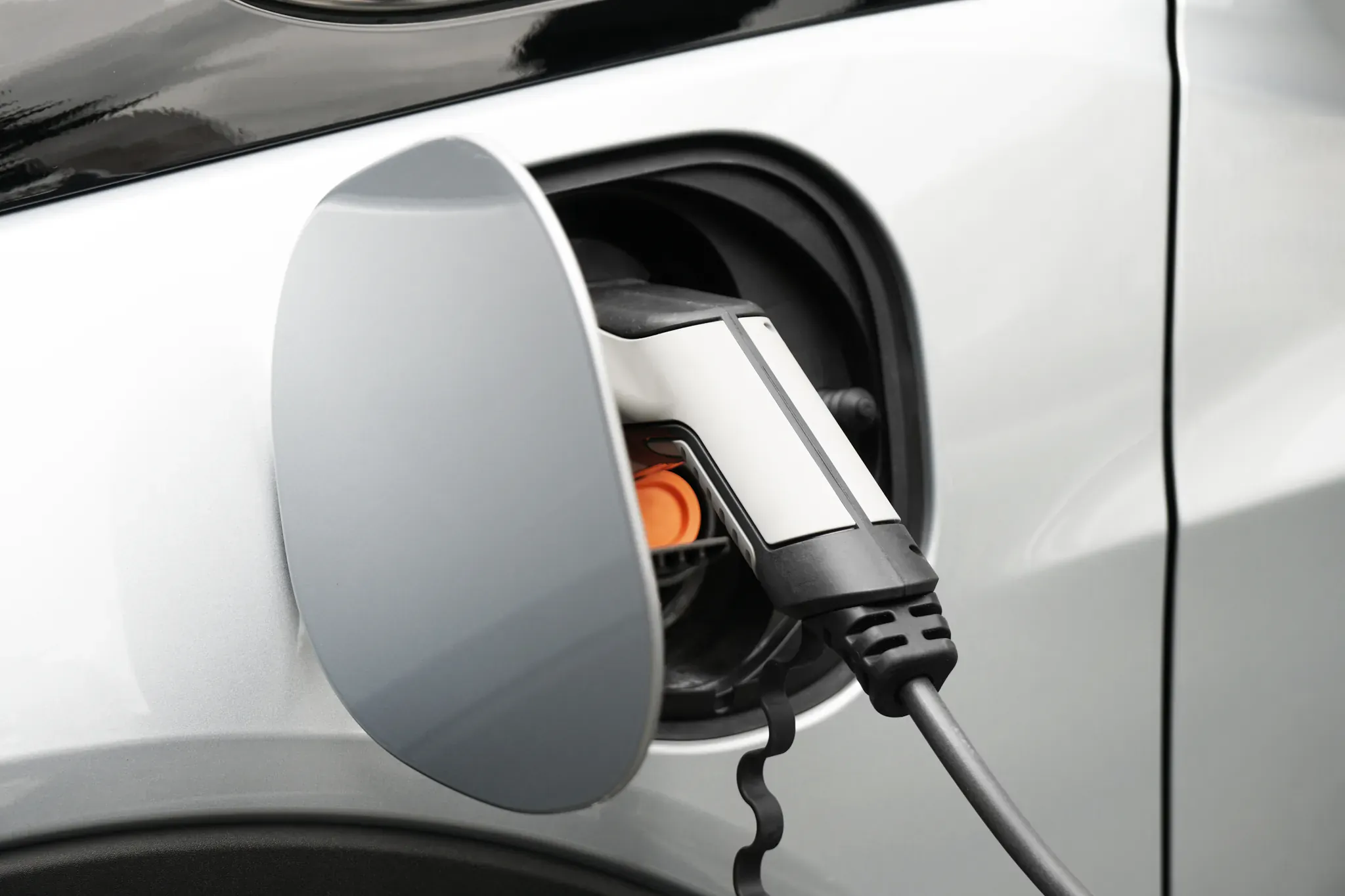 Gros plan sur le connecteur de recharge branché sur une voiture électrique grise