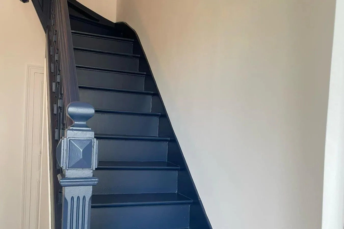 Cage d'escalier repeinte : murs blancs, escalier bleu