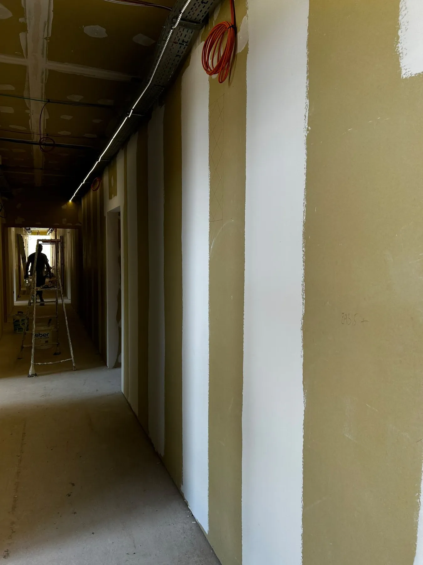 Long couloir aux murs bandés, un ouvrier au fond du chantier