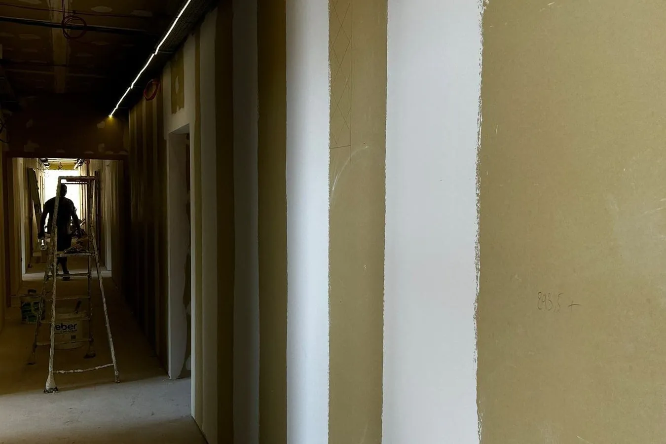 Long couloir aux murs bandés, un ouvrier au fond du chantier
