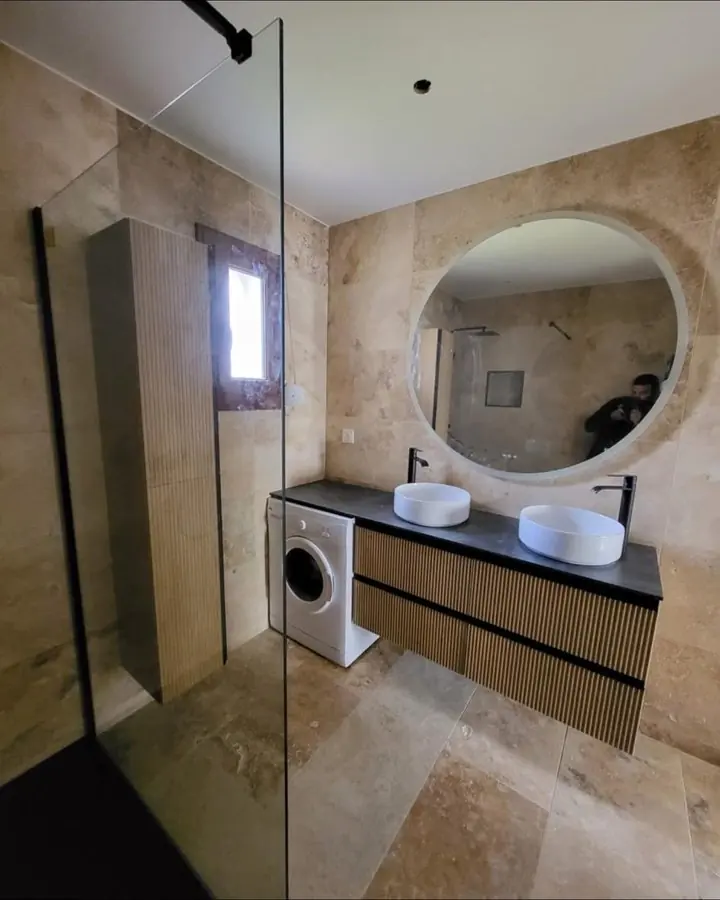 Salle de bain en travertin beige avec douche à l'italienne vitrée et meuble double vasque