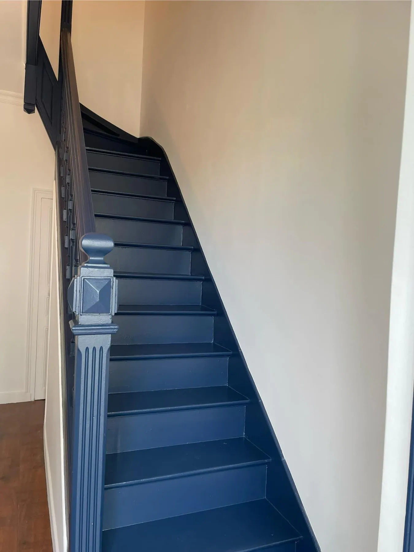 Cage d'escalier repeinte : murs blancs, escalier bleu