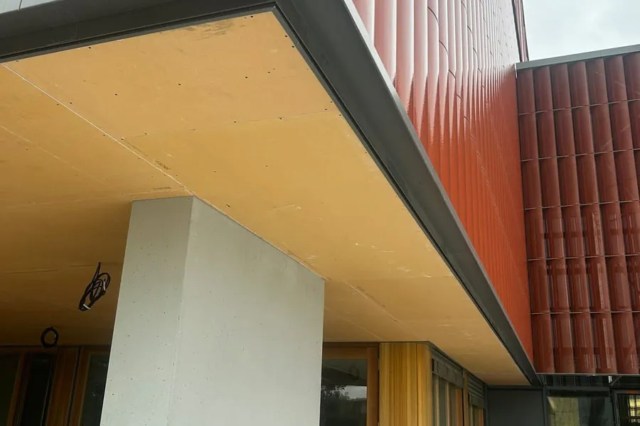 Bâtiment contemporain vu en contre-plongée, avec un auvent dont la sous-face forme un plafond extérieur