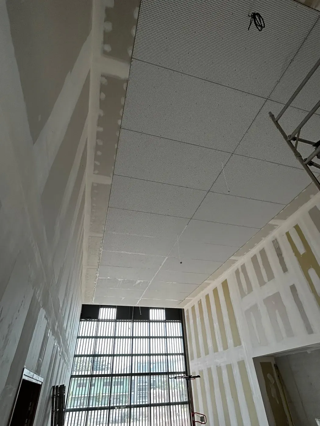Grand hall avec plafond en plaques acoustiques et murs bandés