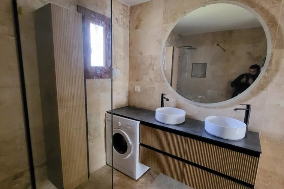 Salle de bain rénovée : double vasque, miroir rond, carrelage pierre