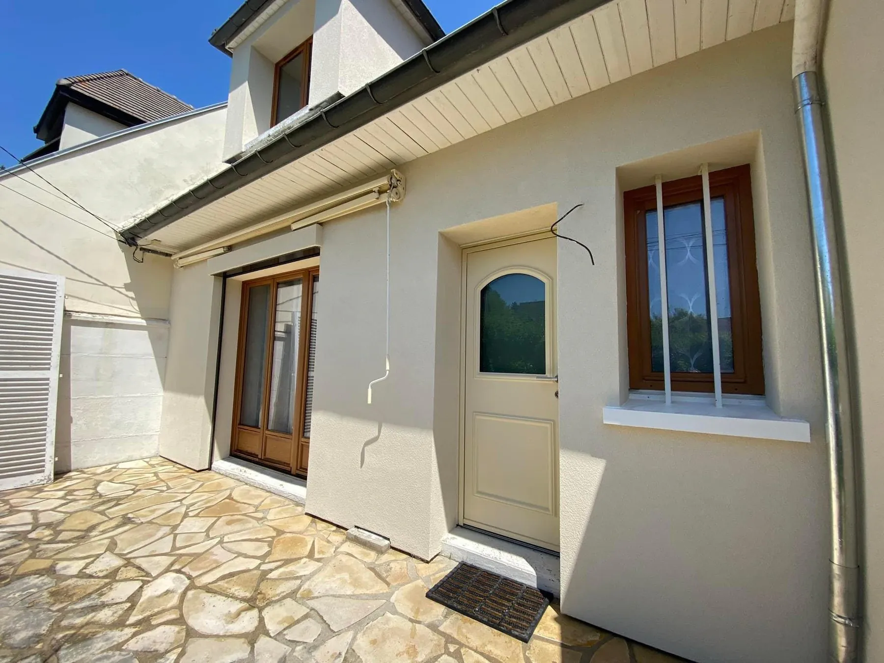 Façade de maison après l'enduit, teinte claire et menuiseries bois