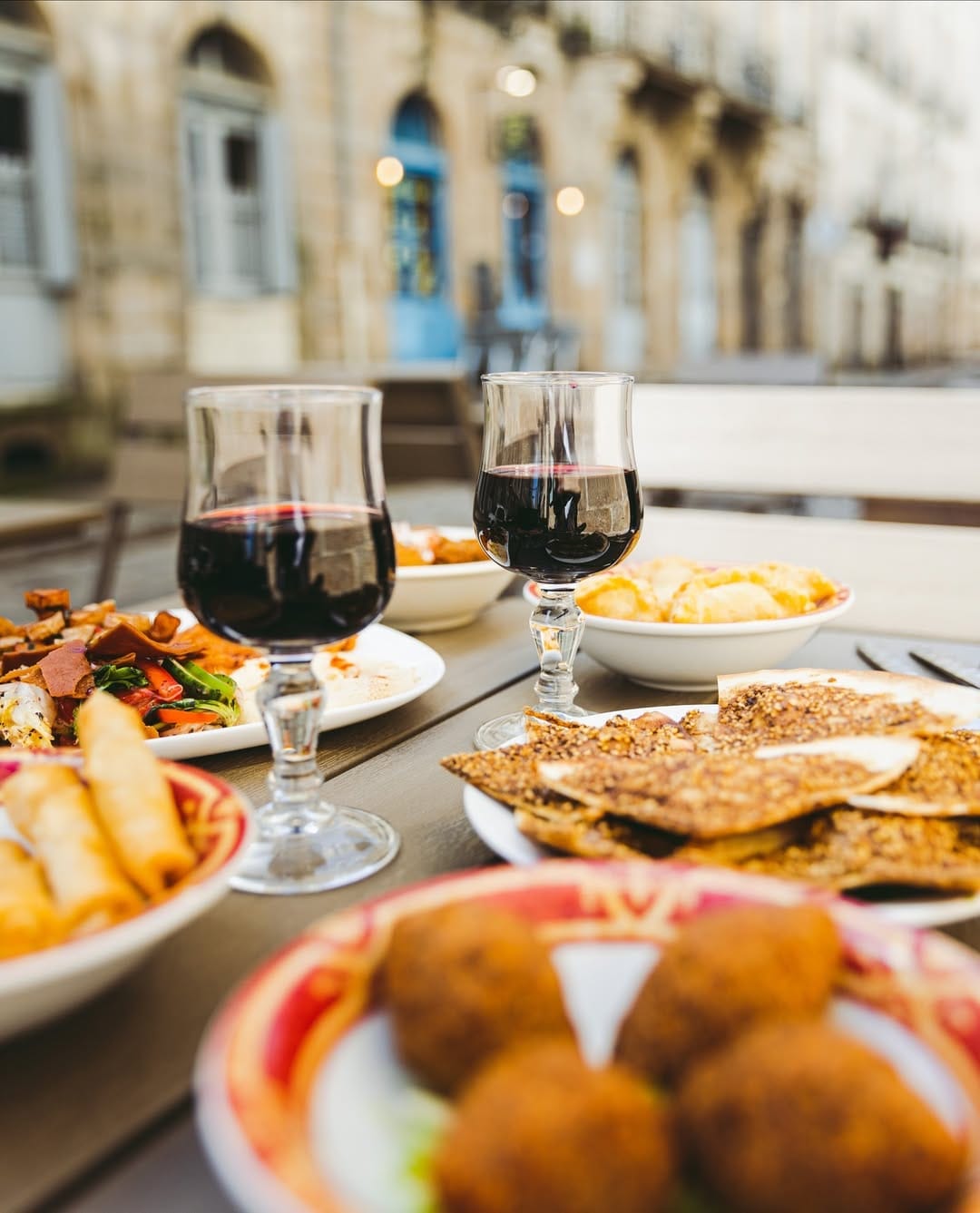 Vue depuis la terrasse rue Kervegan, deux verres de vin et mezzés en premier plan, façade nantaise au fond