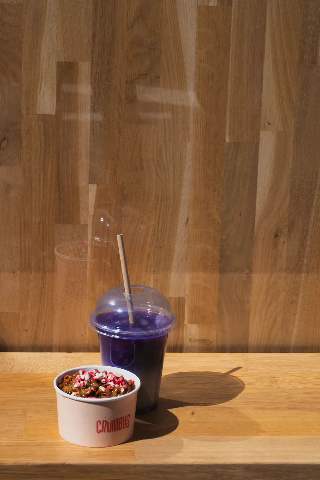 Une boisson et un dessert Crumbles posés sur un rebord en bois