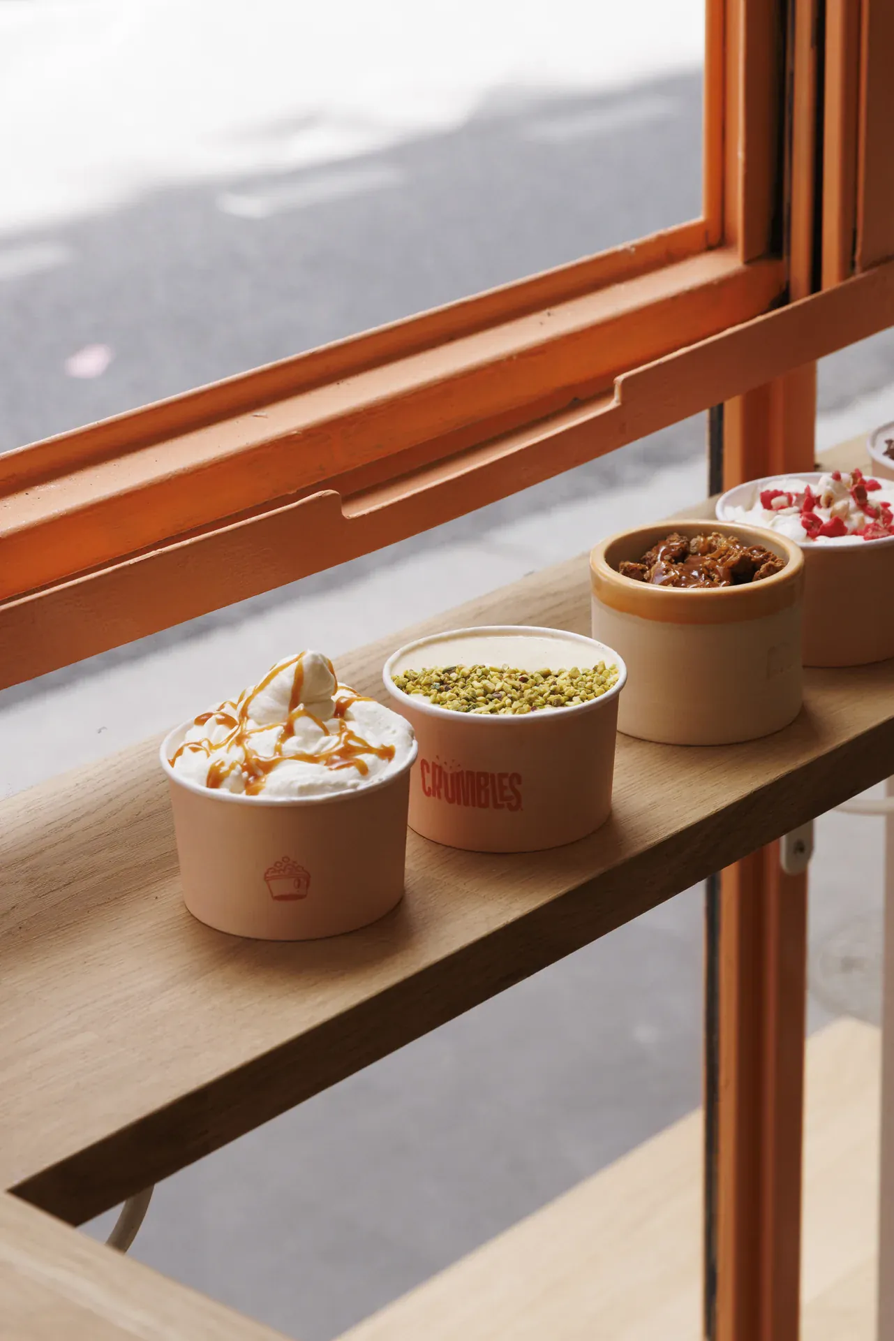 Des crumbles en pots garnis de chantilly, caramel et pistaches, préparés au comptoir Crumbles