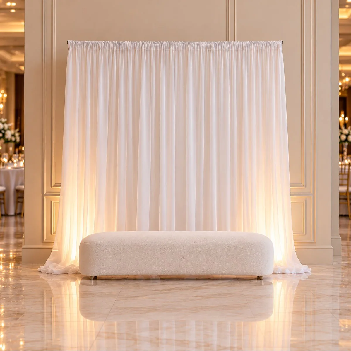 Coin des mariés : banquette blanche bouclée devant un backdrop en voilage blanc éclairé par l'arrière.