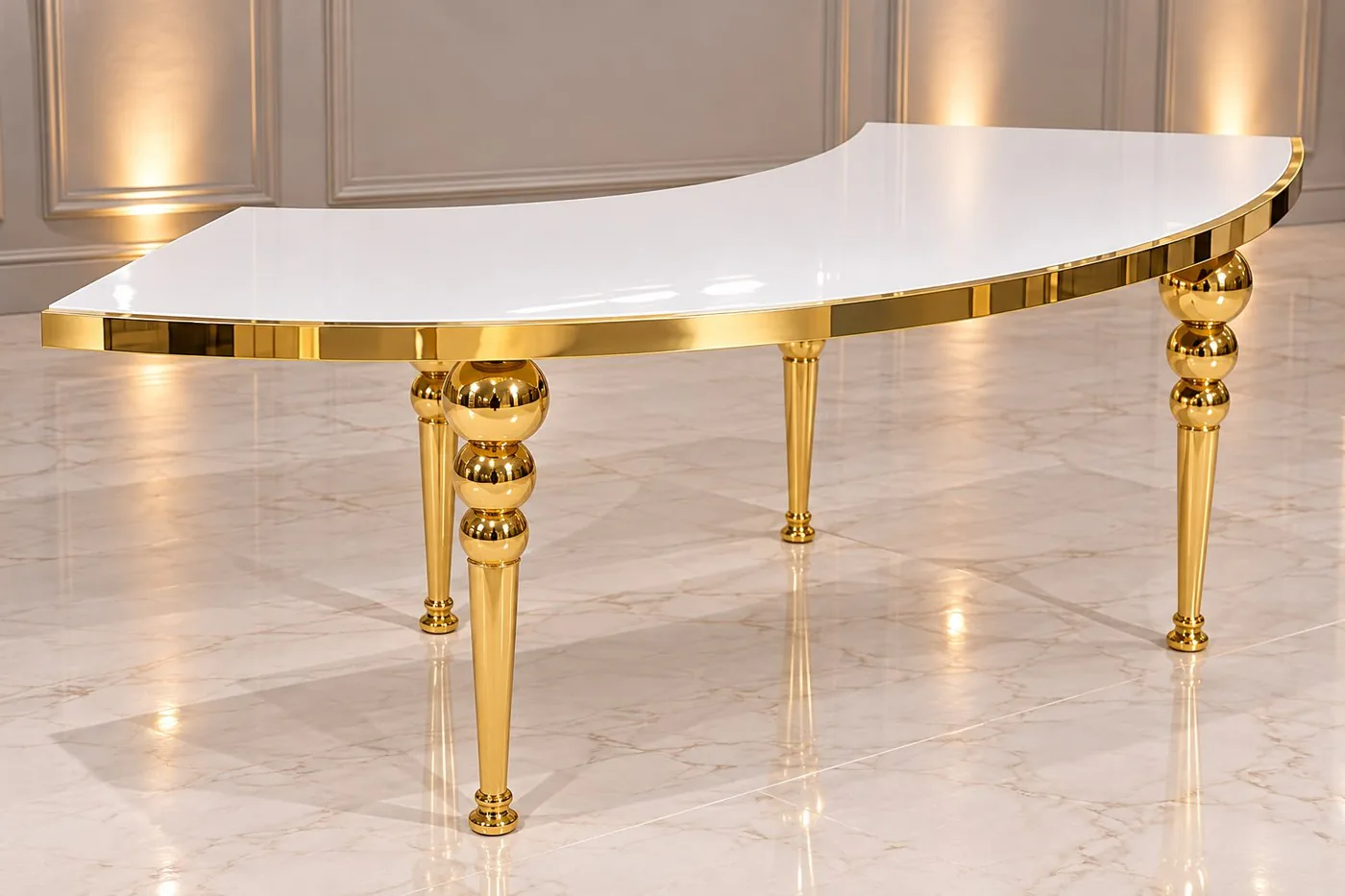 Table en S au plateau blanc laqué cerclé d'or, sur pieds dorés à boules, posée sur un sol en marbre.