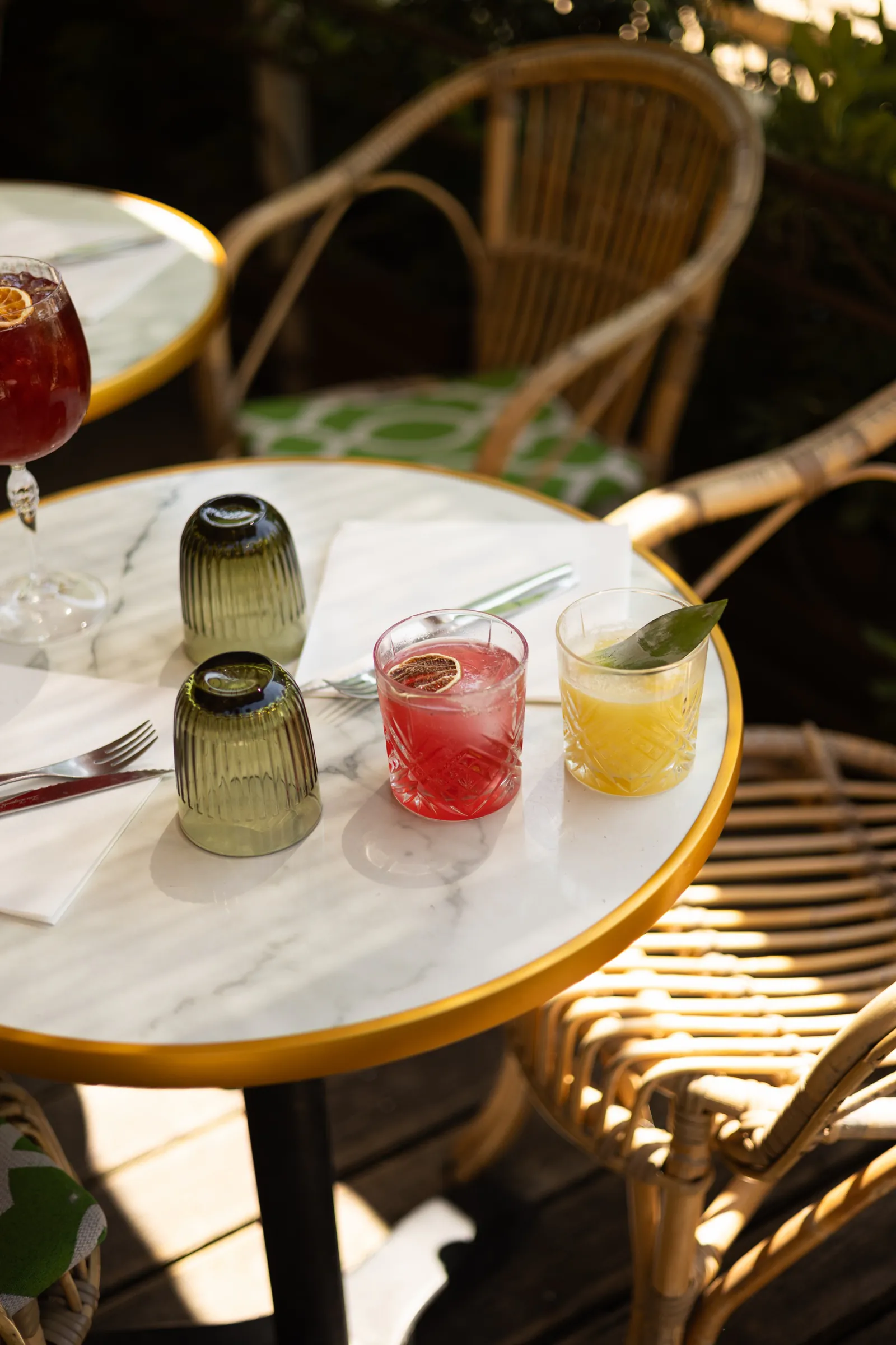 Cocktails servis sur une table de marbre, entre fauteuils en rotin
