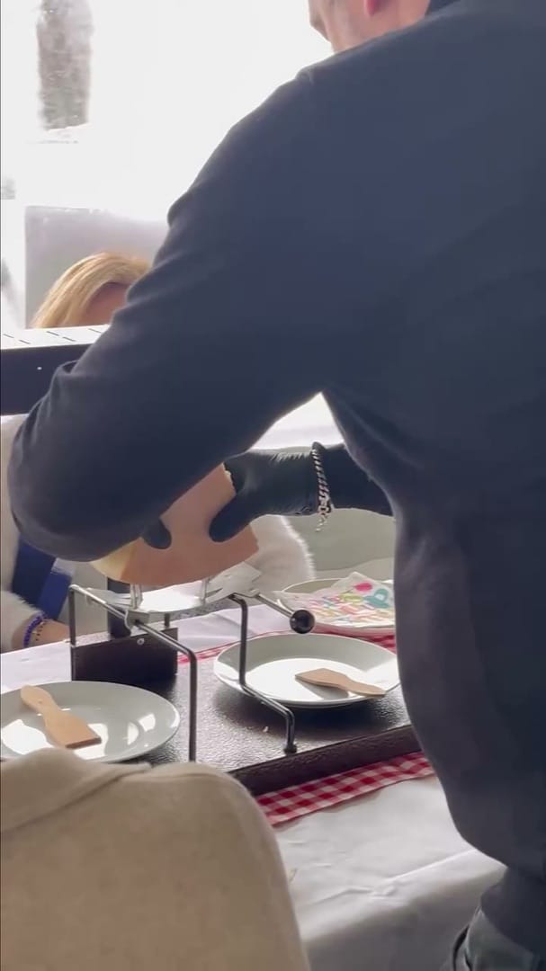 Serveur préparant un plat à partager sur une table dressée, repas convivial de famille en saison fraîche