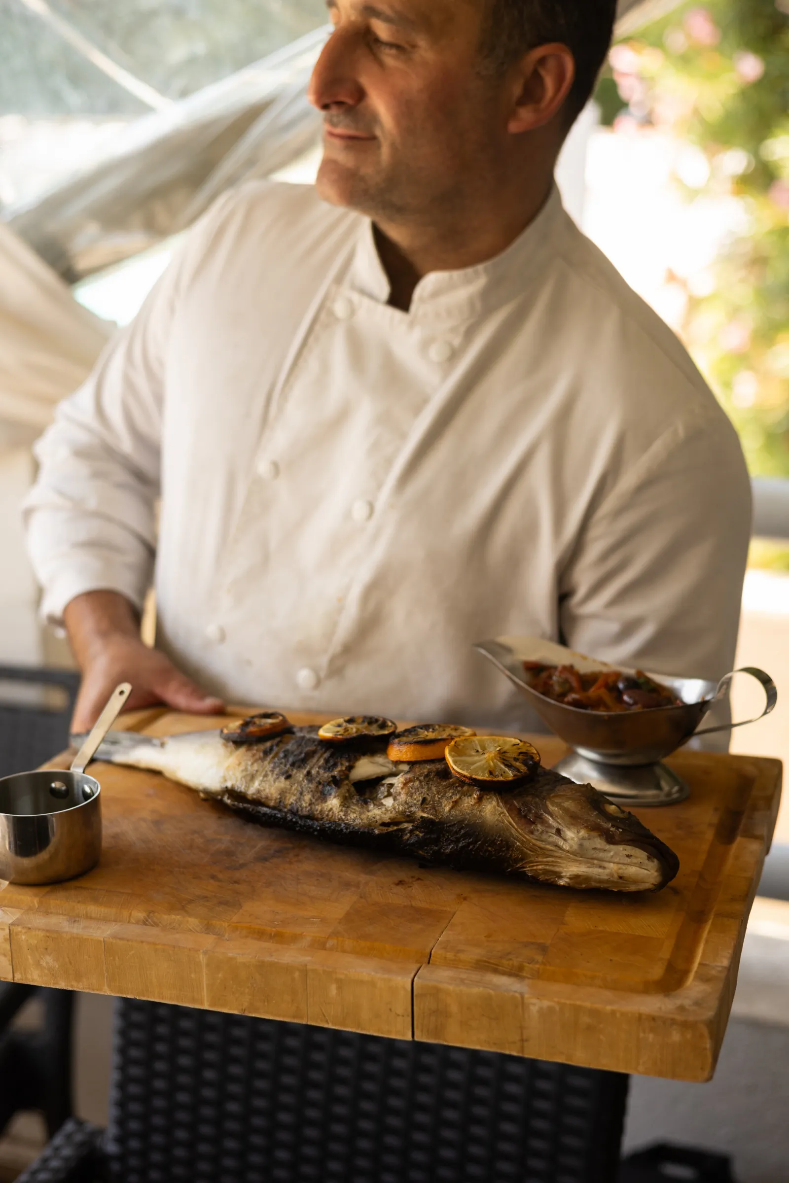 Le chef présente un poisson entier grillé sur sa planche