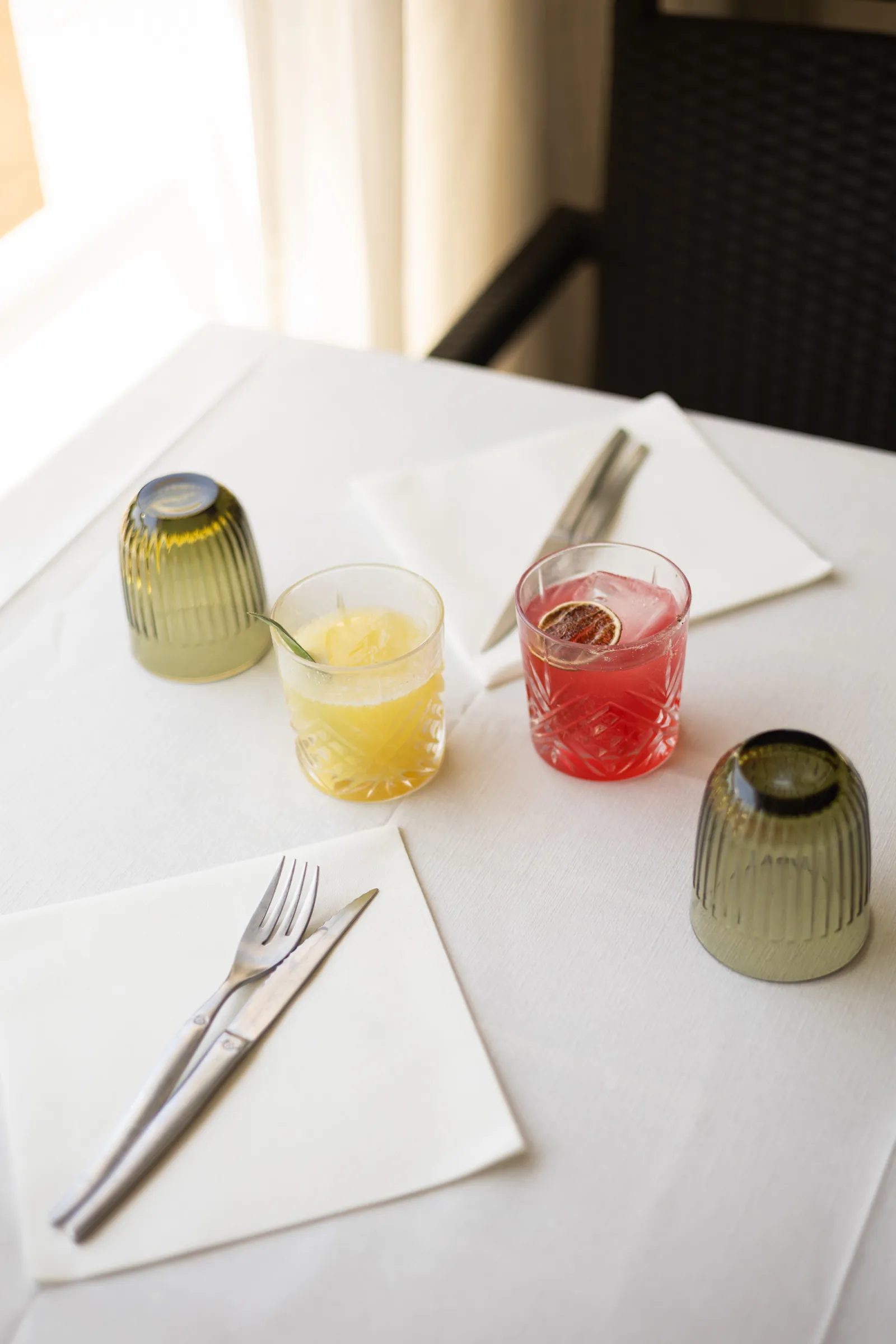 Verres colorés et cocktails posés sur une nappe blanche
