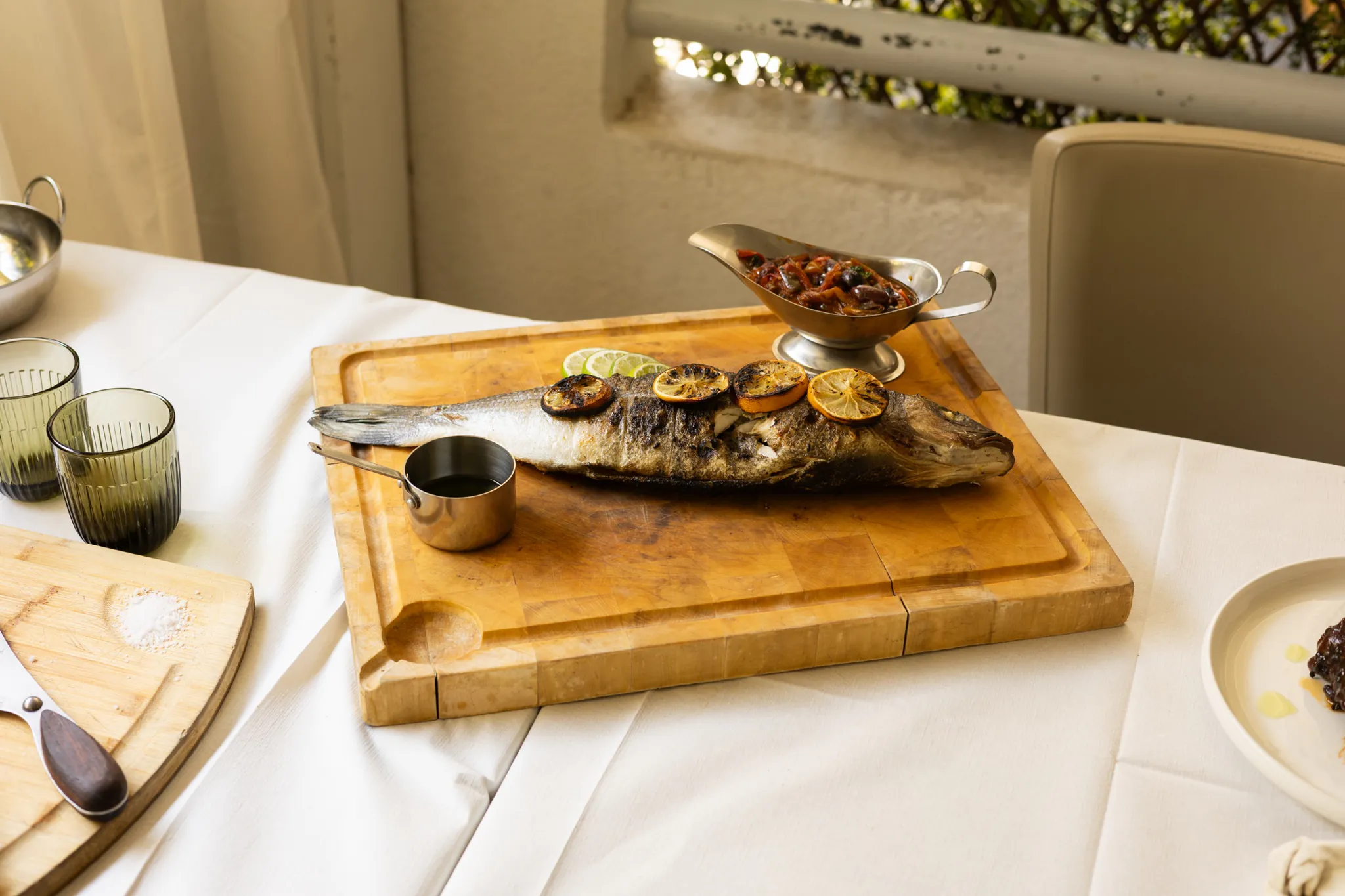 Poisson entier grillé servi sur une table dressée en terrasse