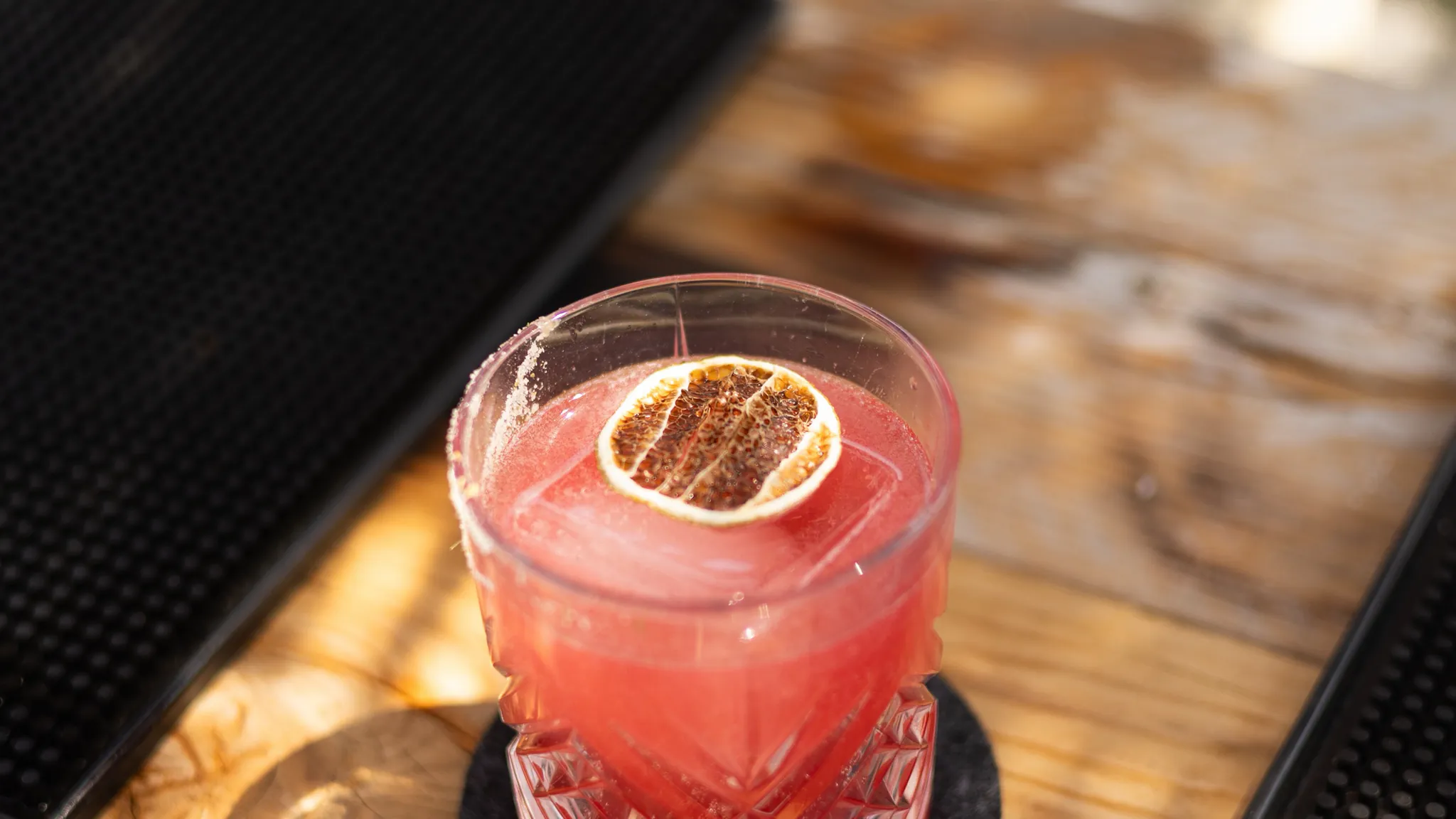 Cocktail signature garni d'une rondelle d'orange séchée, au bar pour l'afterwork à La Paillote