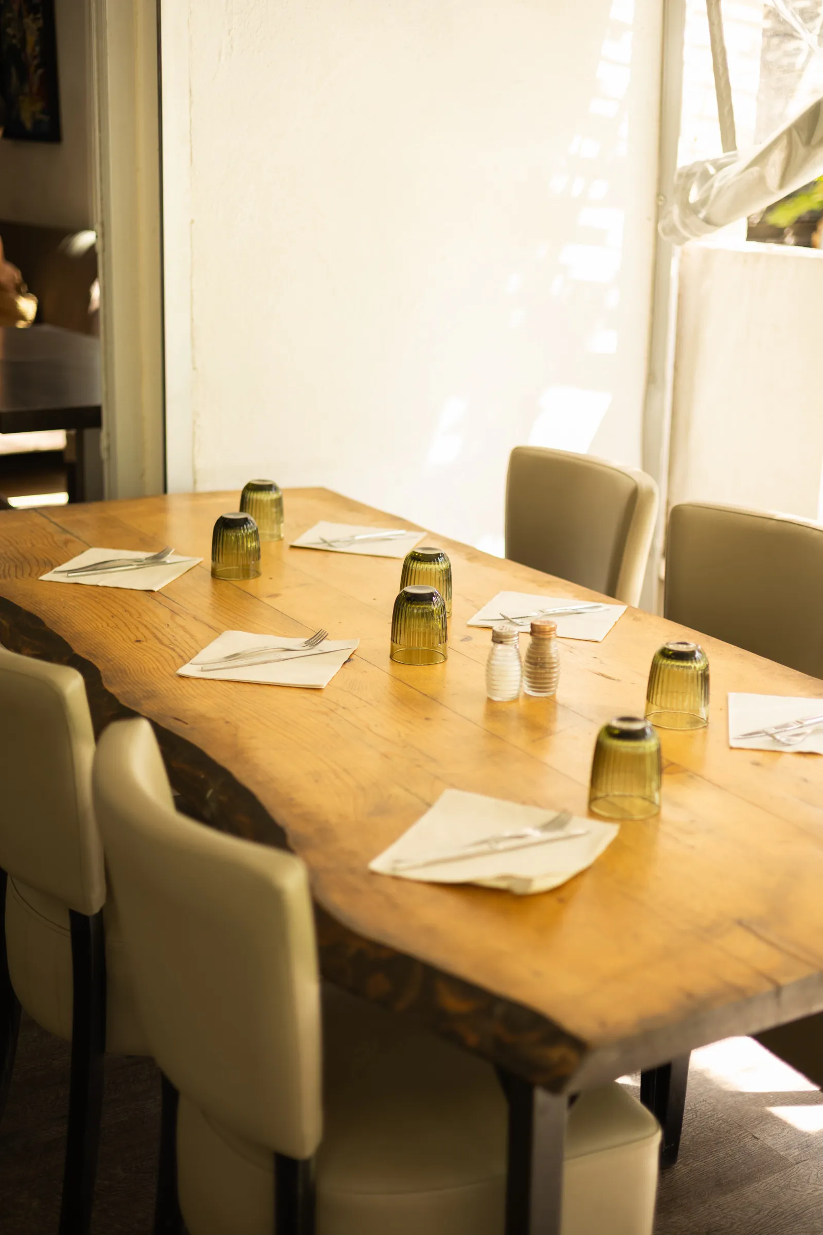 Table en bois brut dressée dans la salle, lumière de fin de journée